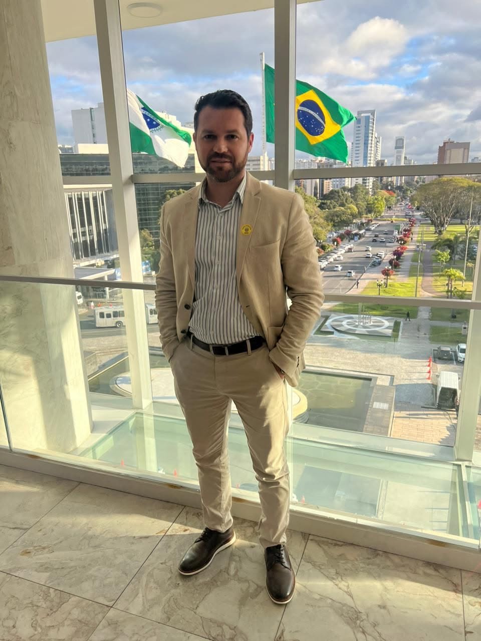 Robson Gutebil em ambiente institucional, diante das bandeiras do Paraná e do Brasil